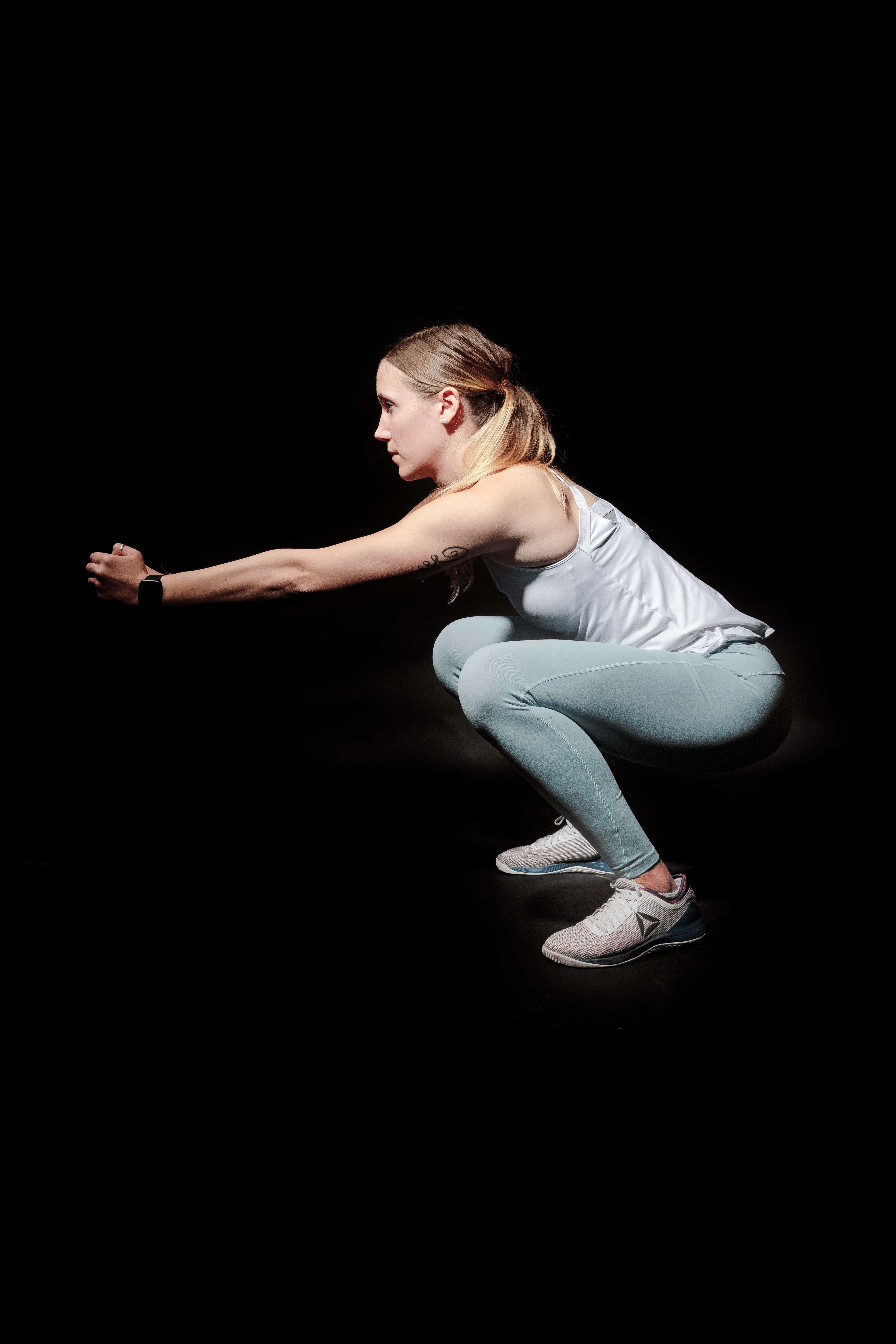 woman doing squats against black back drop